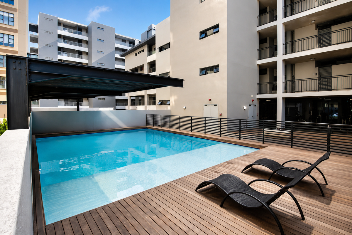 Modern apartment complex pool area featuring a swimming pool, timber decking, and a steel pergola structure.