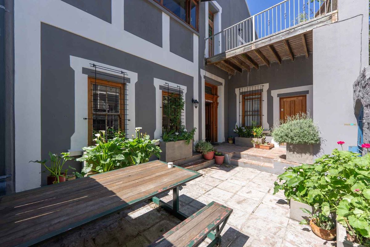 A private rear courtyard featuring stone paving, a raised balcony with metal railings, and traditional timber-framed windows with security bars.