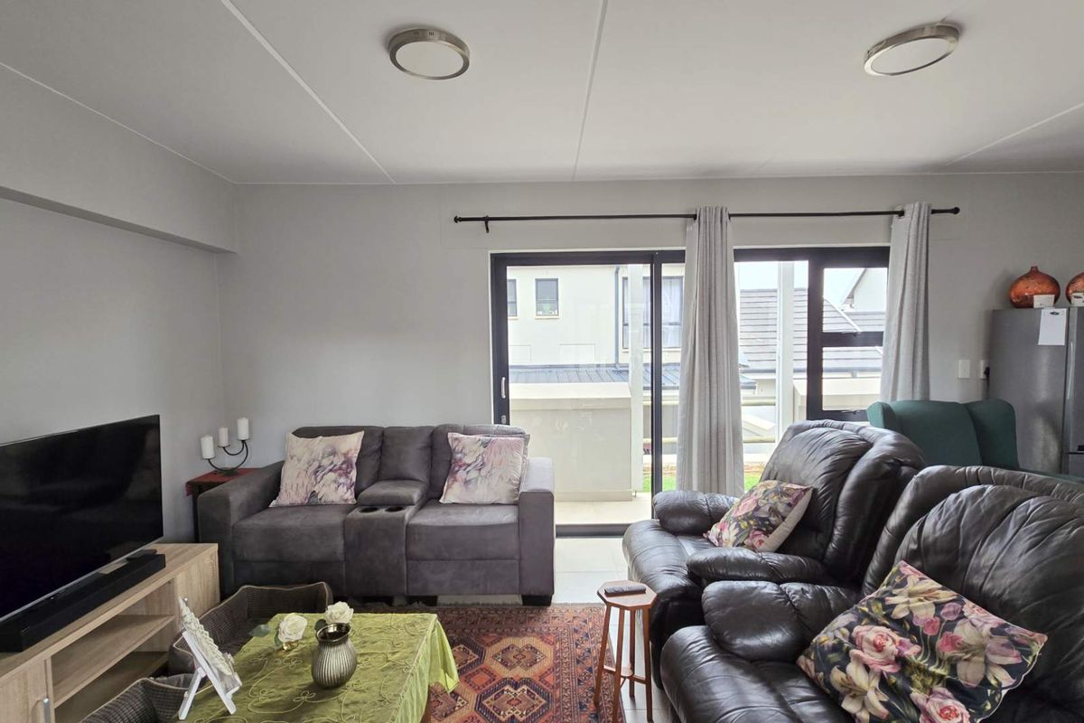 A spacious living area featuring tiled flooring, neutral walls, and large sliding glass doors that provide access to an outdoor balcony.