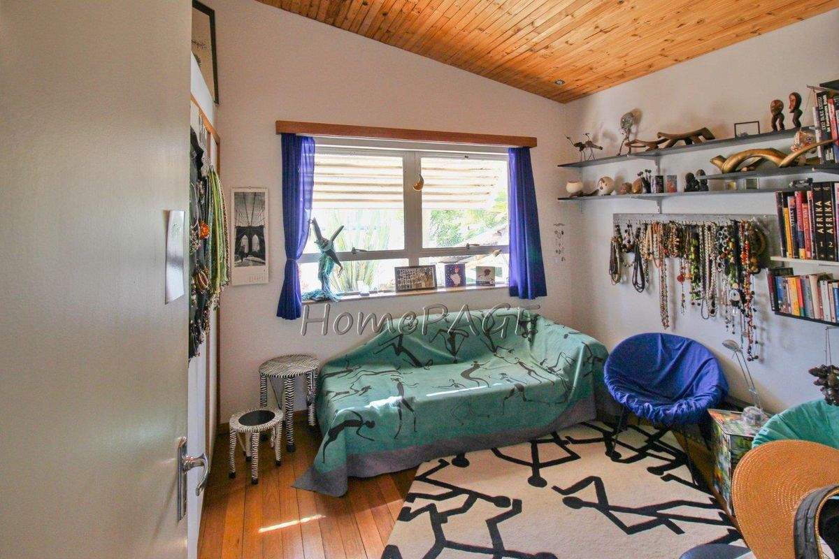 A bedroom featuring a vaulted timber-clad ceiling, wooden flooring, and a window providing natural light.