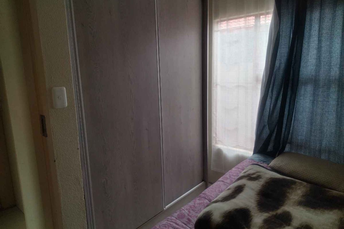 A bedroom featuring built-in sliding door cupboards and natural light from the adjacent window.
