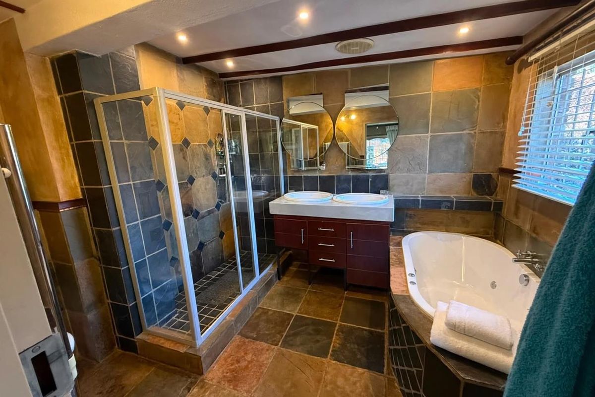 A spacious bathroom featuring a double vanity, a separate shower enclosure, and a built-in bathtub, finished with rustic slate wall and floor tiles.