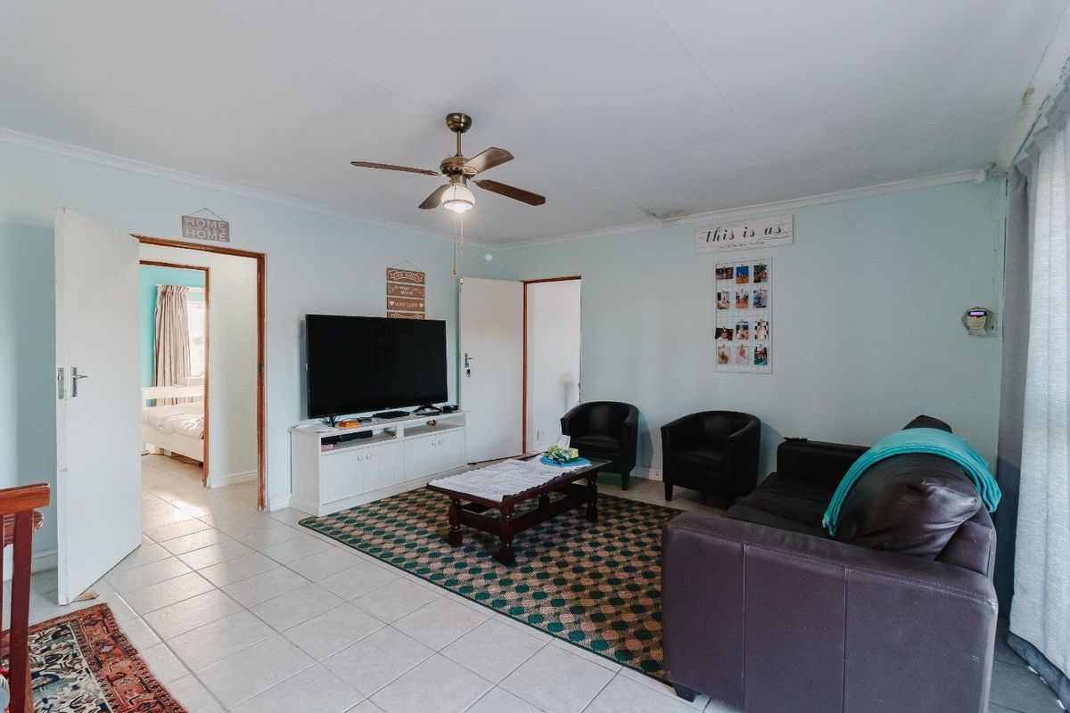 A living room featuring tiled flooring, a ceiling fan, and coved cornicing, with a visible water stain on the ceiling.