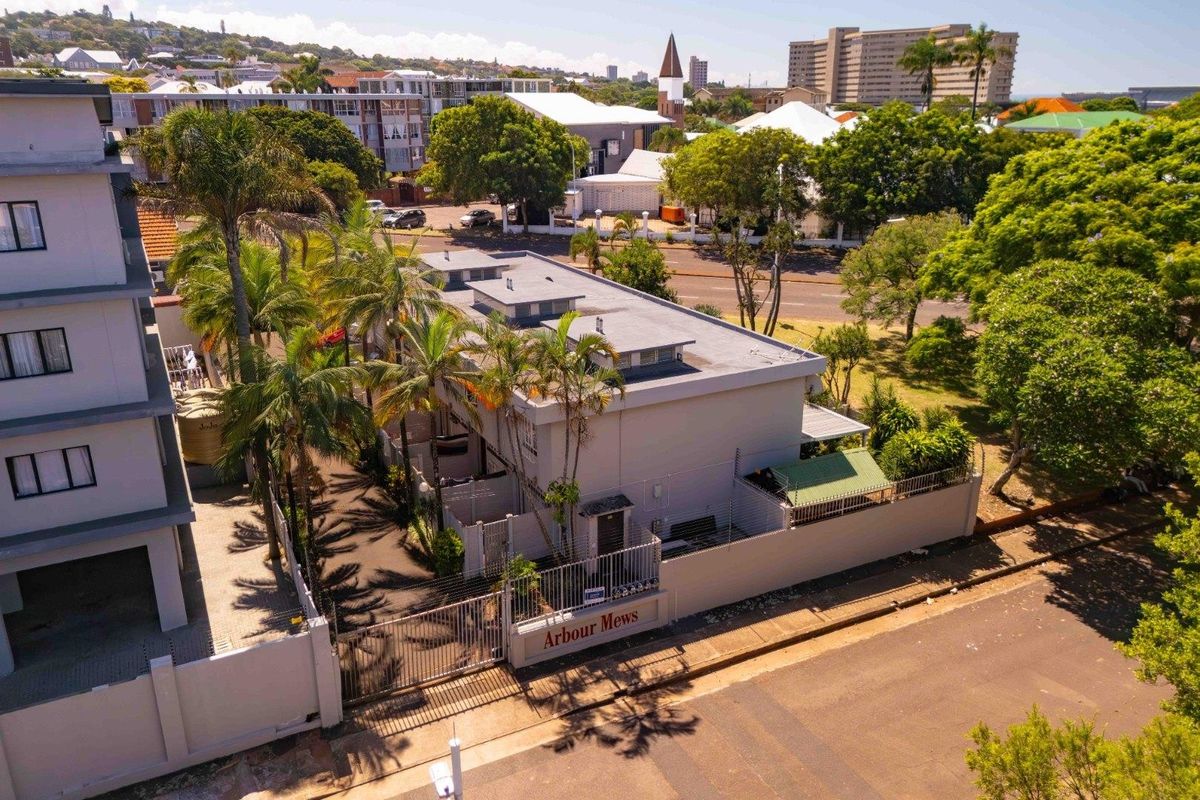 Aerial view of the Arbour Mews townhouse complex, featuring a secure gated entrance, perimeter walling, and established landscaping in a suburban setting.