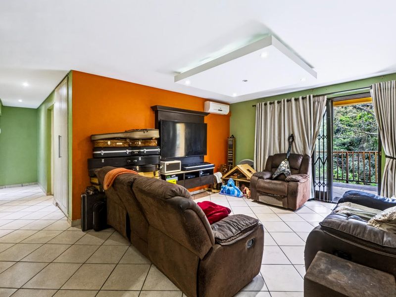 Spacious living room featuring tiled flooring, a recessed ceiling feature with downlights, and direct access to an outdoor balcony through sliding glass doors.