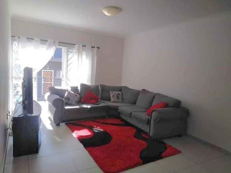A bright living room featuring tiled flooring and a sliding glass door that provides access to an outdoor balcony area.