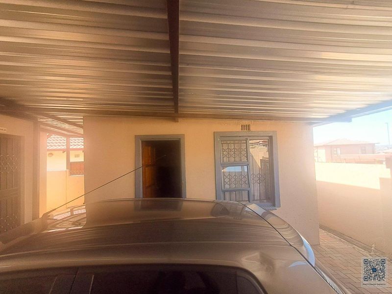 A covered carport area featuring a corrugated metal roof, security gates, and security bars on the windows.
