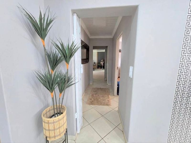 A bright, neutral-toned hallway featuring tiled flooring and a folding door, providing access to the interior living spaces of the home.