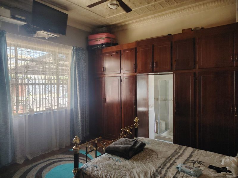 A bedroom featuring extensive built-in wooden cabinetry, an ornate ceiling with a fan, and direct access to an en-suite bathroom.