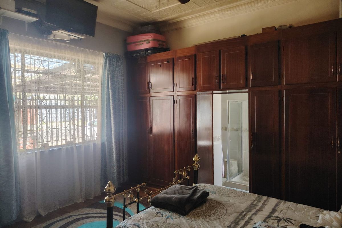 A bedroom featuring extensive built-in wooden cabinetry, an ornate ceiling with a fan, and direct access to an en-suite bathroom.