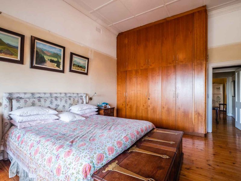 A bedroom featuring polished wooden flooring, extensive floor-to-ceiling built-in wooden cabinetry, and a classic coved ceiling.