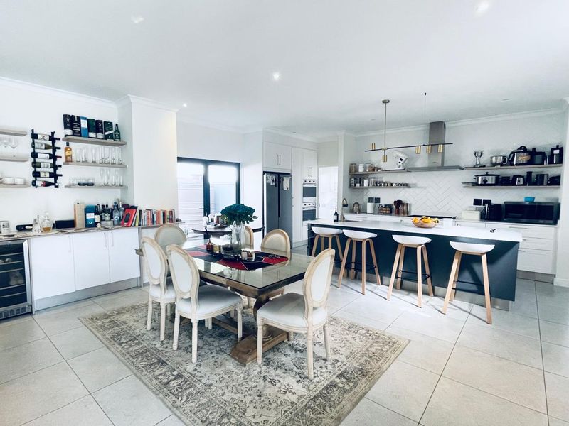 Spacious open-plan kitchen and dining area featuring a large central island, modern cabinetry, herringbone backsplash, and integrated appliances with high-quality finishes.