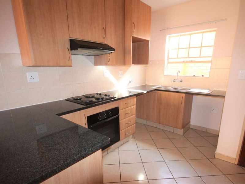 Functional kitchen featuring laminate cabinetry, granite countertops, built-in oven, electric hob, extractor fan, and tiled flooring.