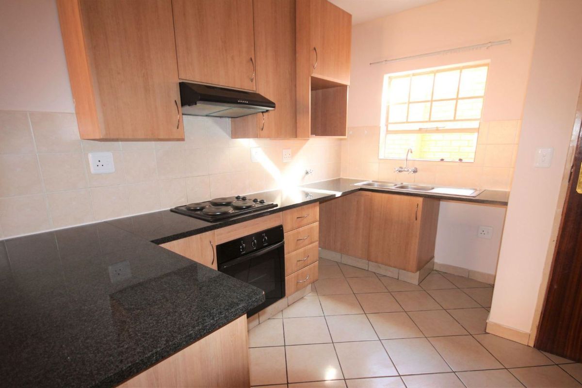 Functional kitchen featuring laminate cabinetry, granite countertops, built-in oven, electric hob, extractor fan, and tiled flooring.