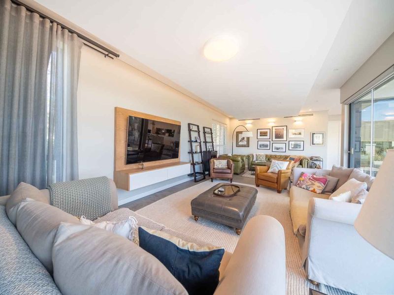 Spacious living room featuring a modern floating media console, recessed lighting, and large sliding glass doors that provide ample natural light.