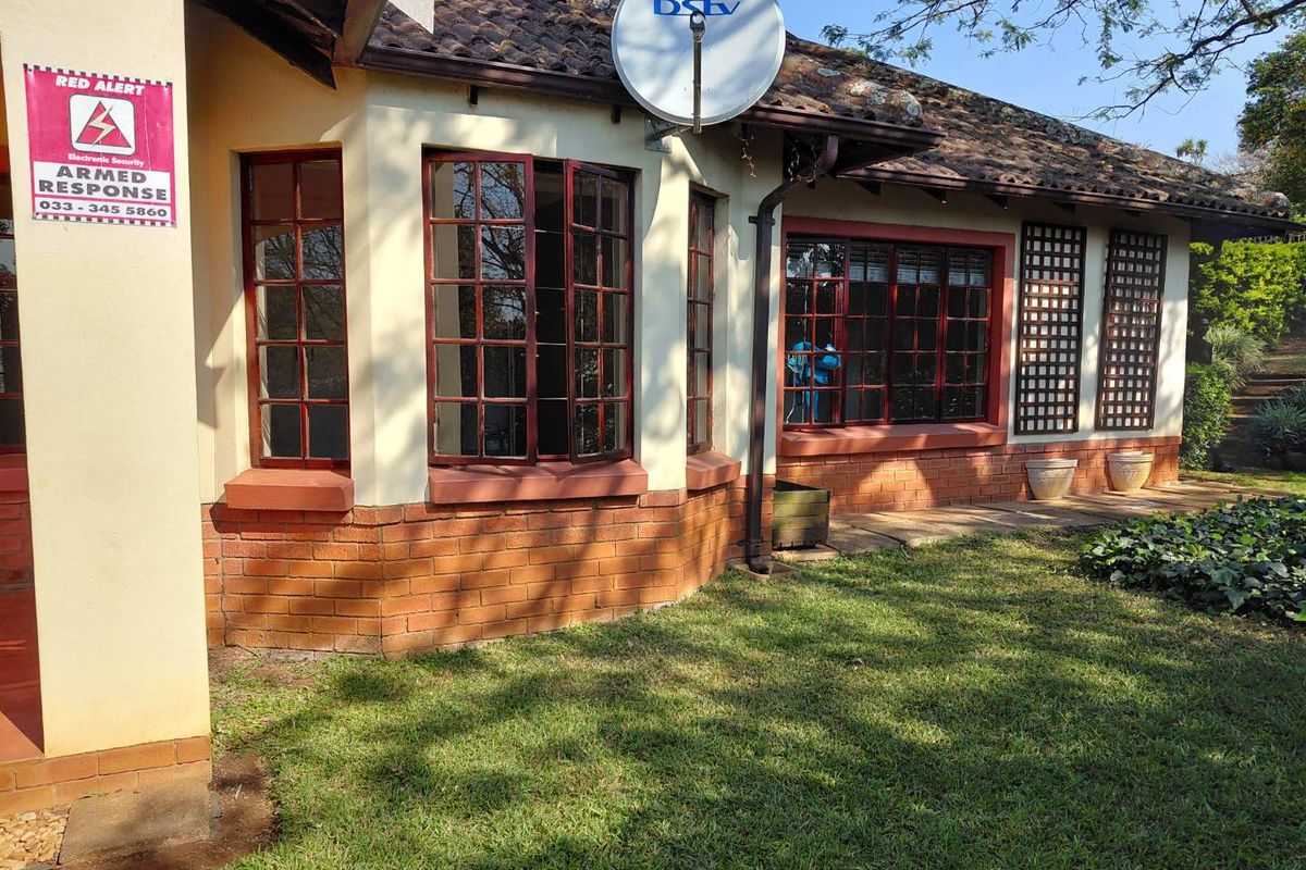 Rear exterior view of the townhouse featuring a tiled roof, brick base, and timber-framed windows set against a garden area.