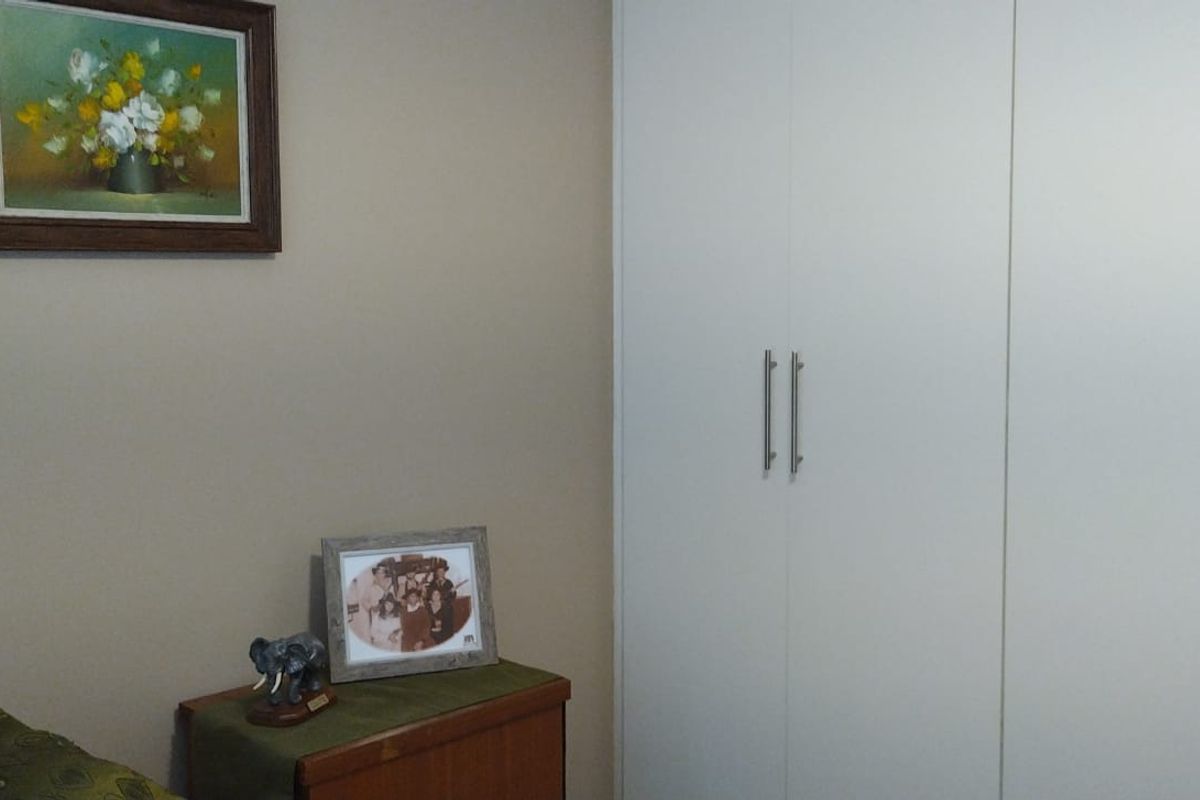 A bedroom featuring built-in white cabinetry with modern handles, providing ample storage space.