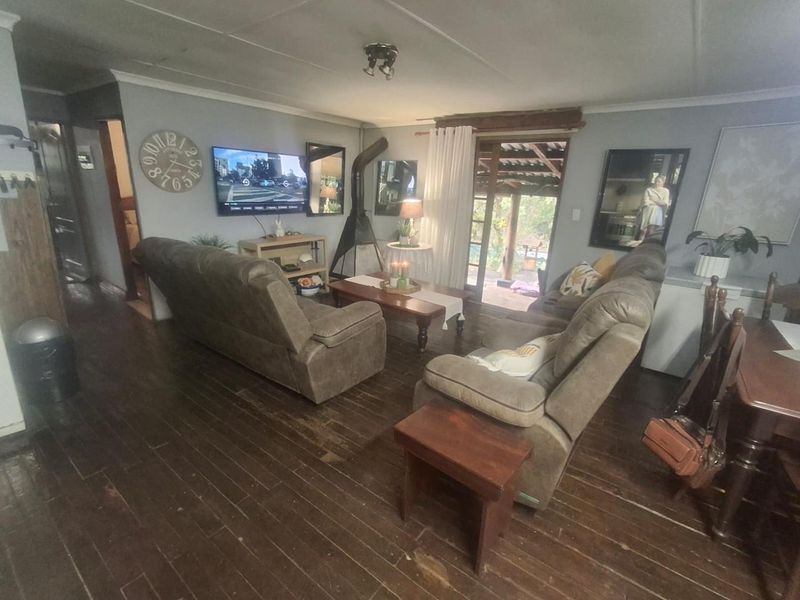 A living room featuring hardwood flooring, a wood-burning fireplace, and direct access to an outdoor patio area through sliding glass doors.