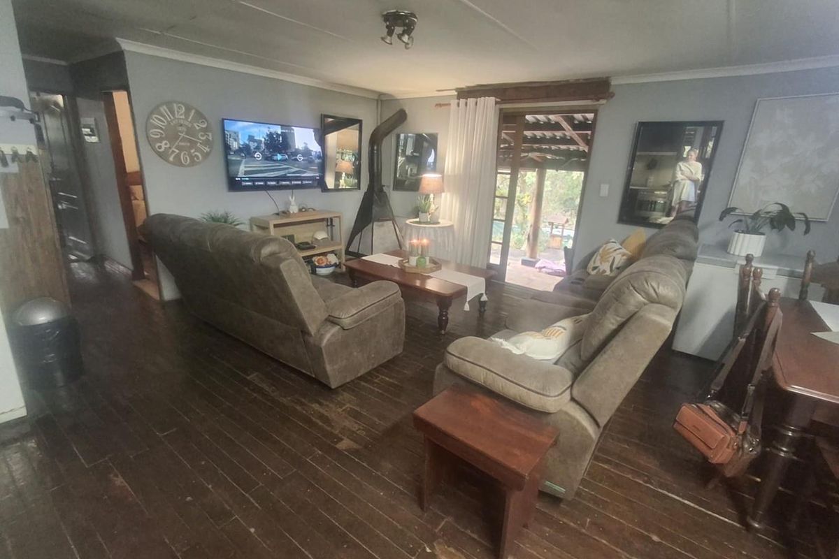 A living room featuring hardwood flooring, a wood-burning fireplace, and direct access to an outdoor patio area through sliding glass doors.