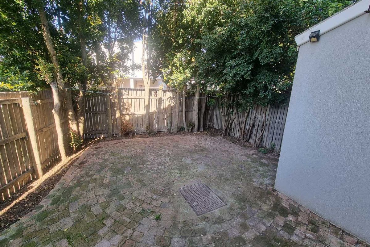A private rear courtyard featuring circular brick paving, enclosed by timber fencing and mature trees, offering a secluded outdoor space.
