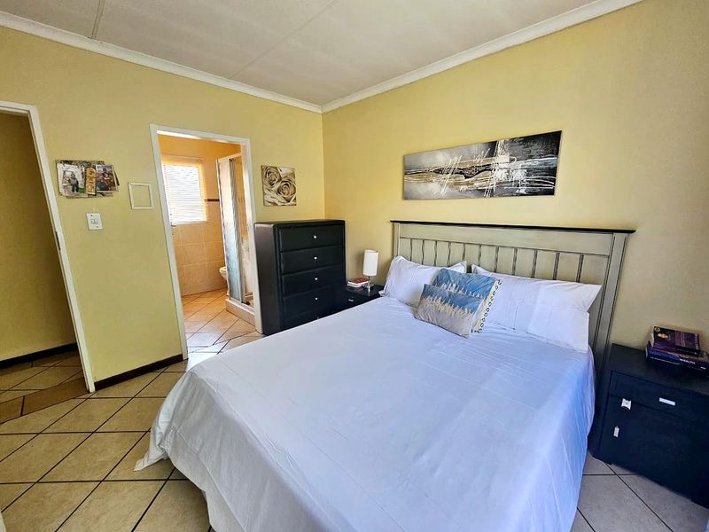 A bedroom featuring tiled flooring and direct access to an en-suite bathroom, offering a functional layout with neutral wall finishes.