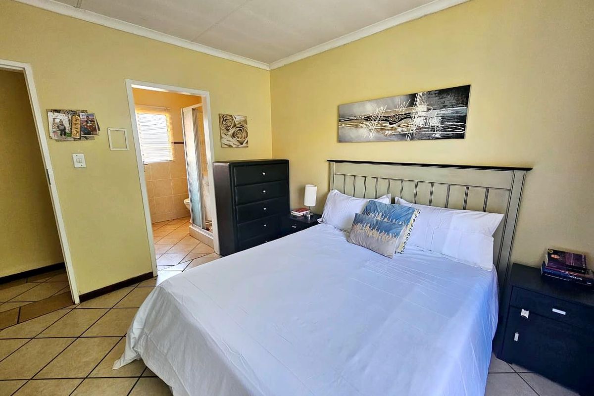 A bedroom featuring tiled flooring and direct access to an en-suite bathroom, offering a functional layout with neutral wall finishes.