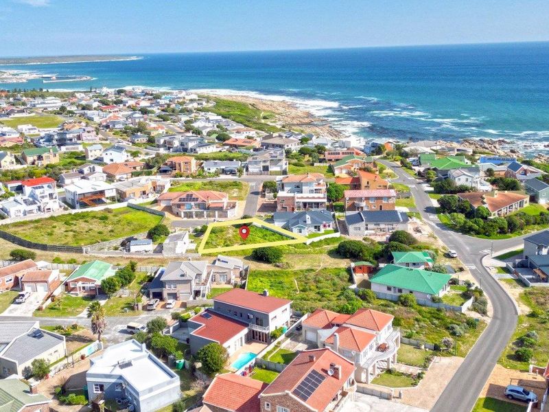 Aerial view of a vacant residential plot situated in a coastal neighborhood, highlighting its proximity to the ocean and surrounding residential development.