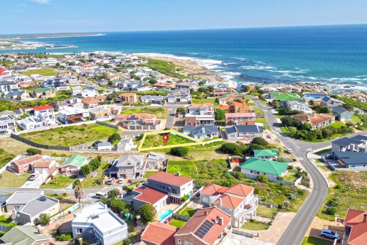 Aerial view of a vacant residential plot situated in a coastal neighborhood, highlighting its proximity to the ocean and surrounding residential development.