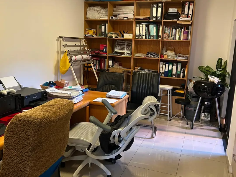 A functional home office space featuring tiled flooring and a large built-in wooden shelving unit for storage.