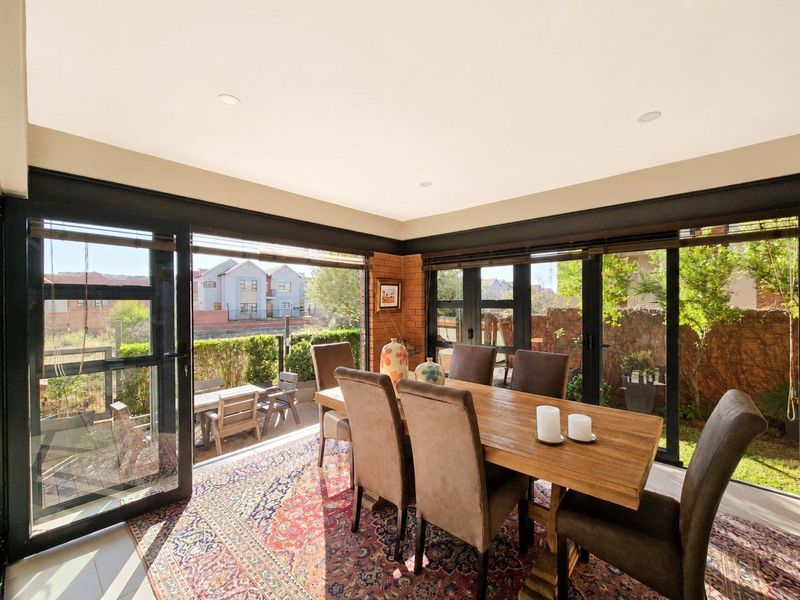 Bright dining area featuring exposed brick walls and large black aluminium sliding doors providing seamless access to the outdoor patio and garden.