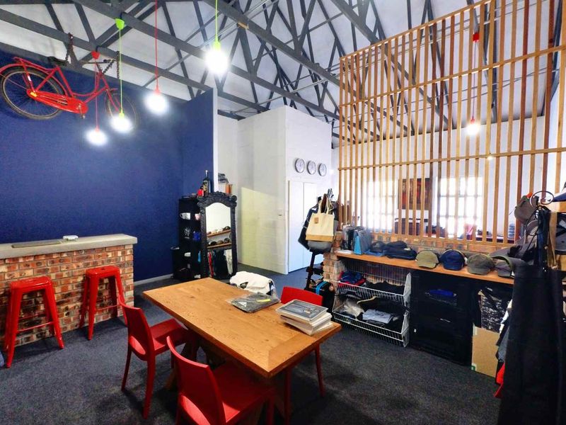 Open plan industrial space featuring exposed steel roof trusses, a brick bar counter, and a decorative timber slat room divider.