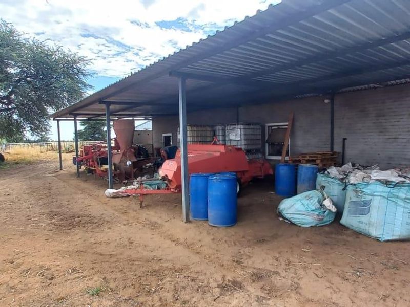 A functional open-sided utility shed with a corrugated metal roof and steel support structure, suitable for farm equipment storage and general agricultural use.