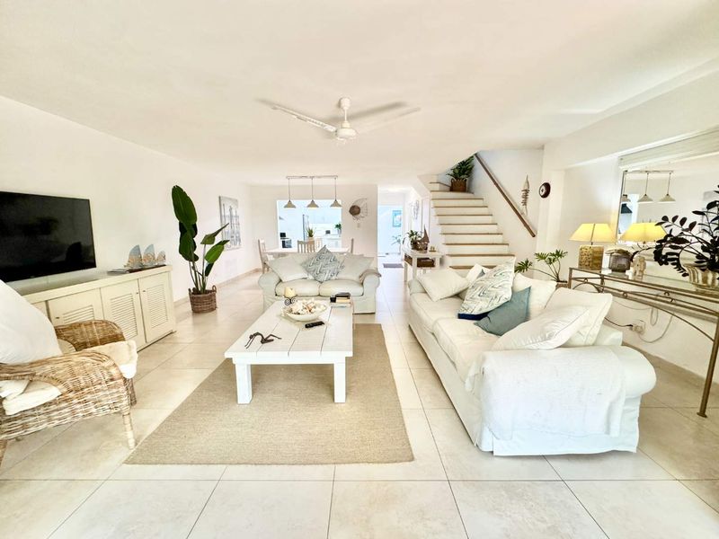Spacious open-plan living area featuring neutral tiled flooring, a central staircase, and integrated ceiling fan, flowing seamlessly into the dining and kitchen space.