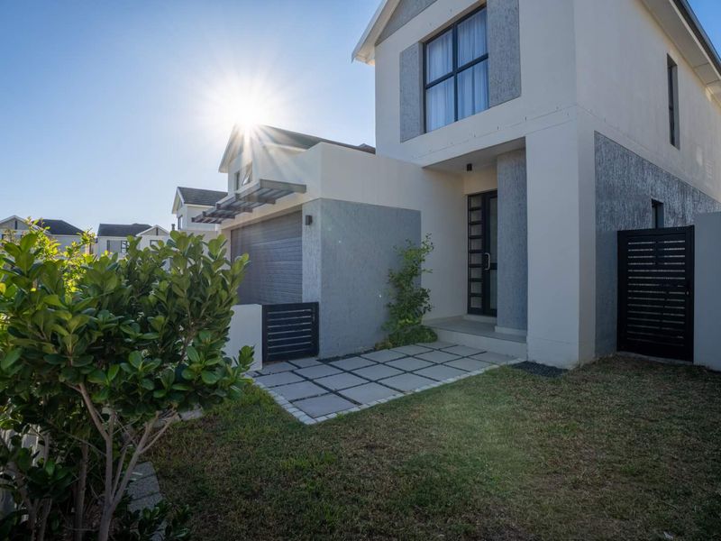 Modern double-storey townhouse exterior featuring a paved entrance walkway, integrated garage, and contemporary facade finishes.