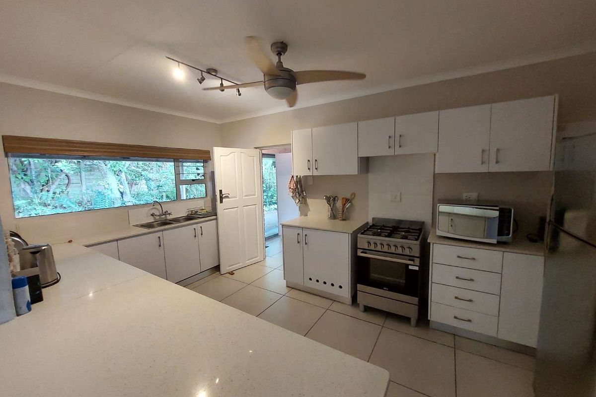 A functional kitchen featuring white cabinetry, quartz countertops, tiled flooring, and a gas stove, with direct access to the exterior.