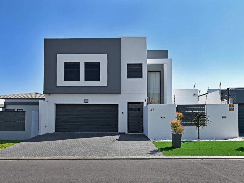 Modern double-story residential property featuring a paved driveway, automated garage, and secure boundary wall with electric fencing.