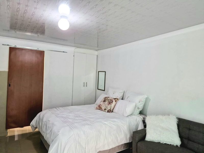 A bedroom featuring a built-in wardrobe, sliding door access, and a glossy ceiling finish with cove cornicing.