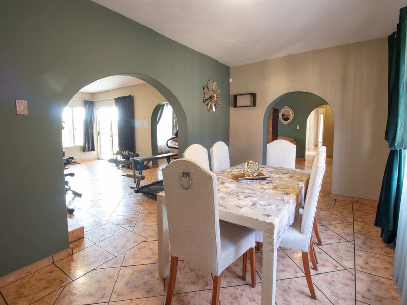 Dining room featuring tiled flooring and distinctive arched doorways leading to adjacent living spaces.