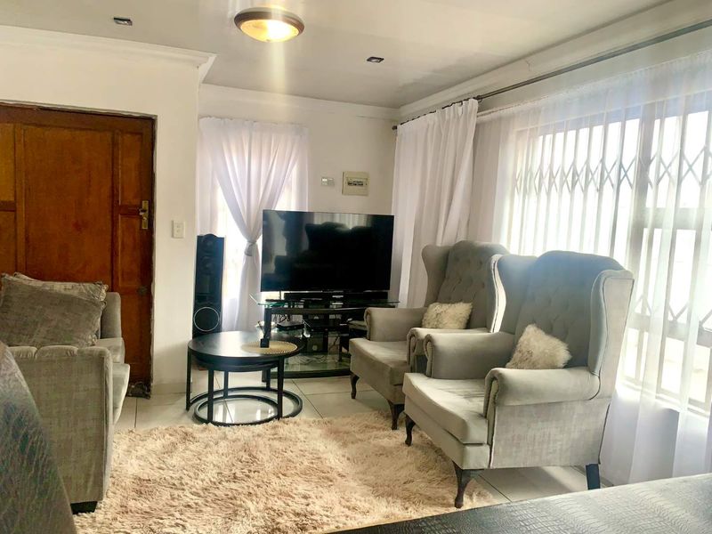 A cozy living room featuring tiled flooring, recessed lighting, and a secure window gate, providing a functional and comfortable space.