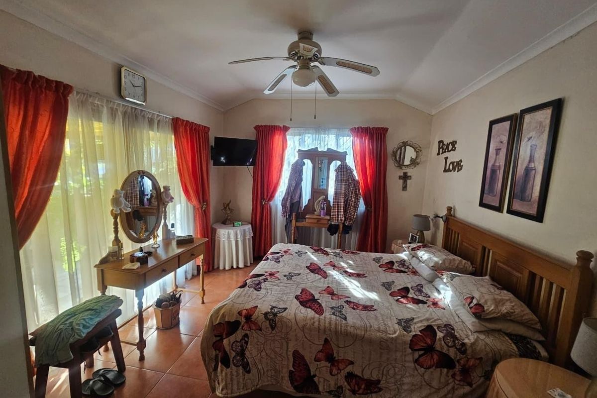 A bedroom featuring tiled flooring, a ceiling fan, and a sliding glass door providing natural light.