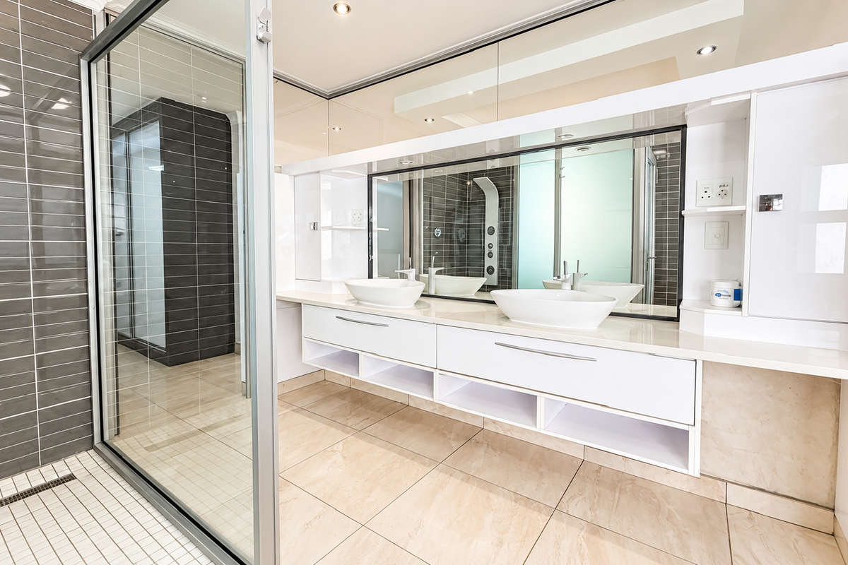 Modern bathroom featuring a sleek double vanity with vessel sinks, large mirror, and a spacious walk-in shower with contemporary tiled finishes.