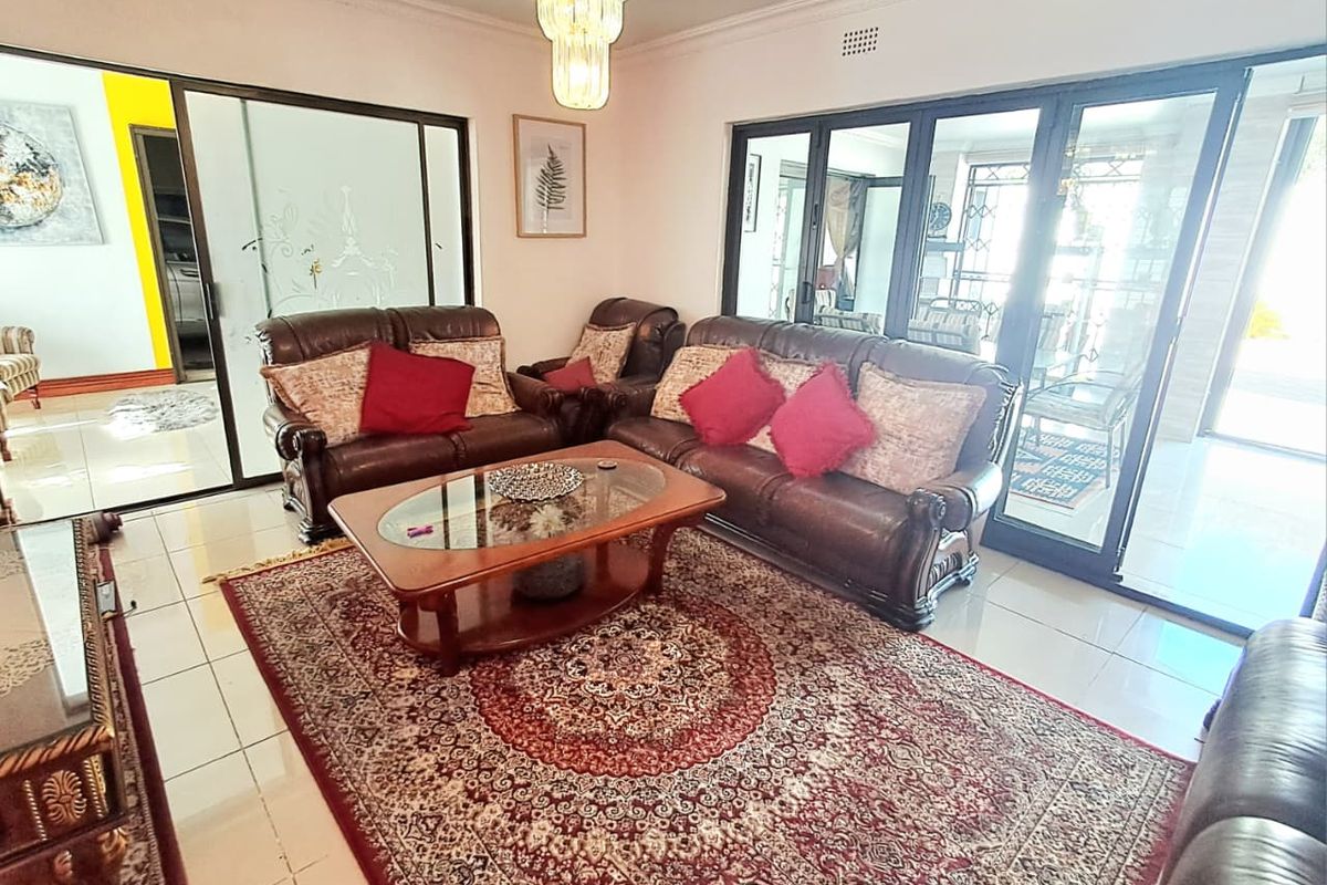 Spacious living room featuring tiled flooring, decorative ceiling cornice, and large sliding glass doors providing access to the outdoor area.