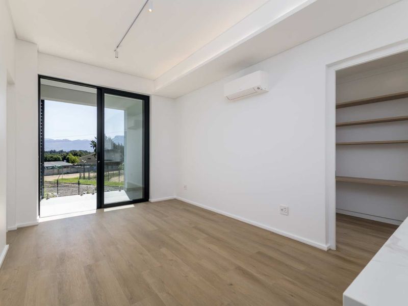 A bright, modern living area featuring laminate flooring, a split-system air conditioner, and a sliding glass door leading to an outdoor space.