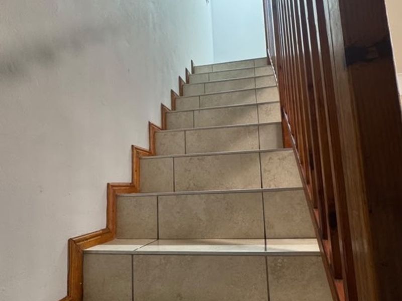 A staircase featuring tiled steps and a wooden balustrade, providing access between levels within the townhouse.