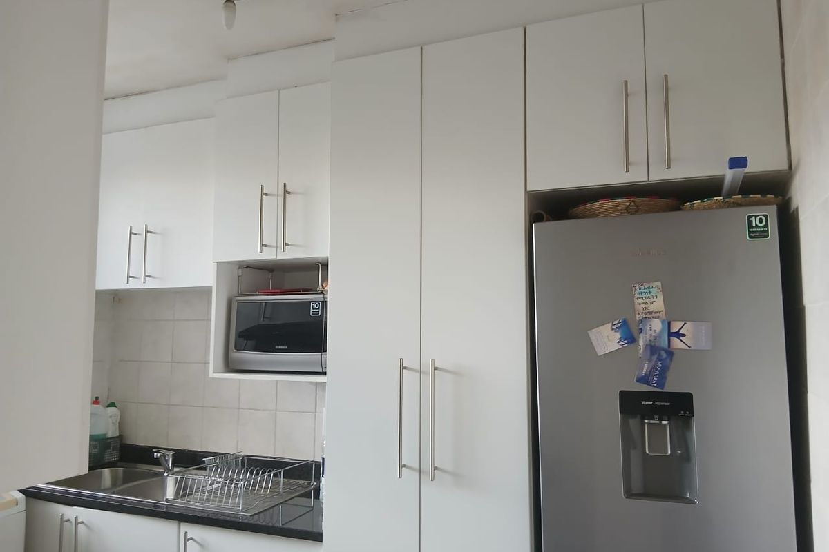 A functional kitchen featuring white cabinetry, granite countertops, a stainless steel sink, and a built-in microwave, with some minor ceiling and fixture maintenance required.