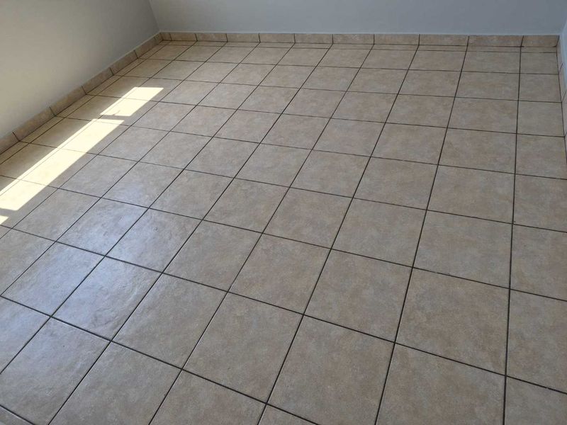 An empty bedroom featuring neutral ceramic floor tiles and matching tiled skirting, providing a clean and versatile space ready for personalization.