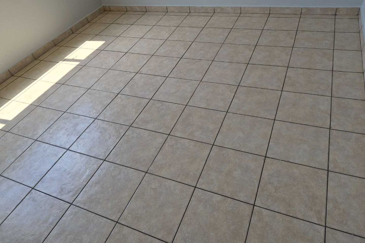 An empty bedroom featuring neutral ceramic floor tiles and matching tiled skirting, providing a clean and versatile space ready for personalization.