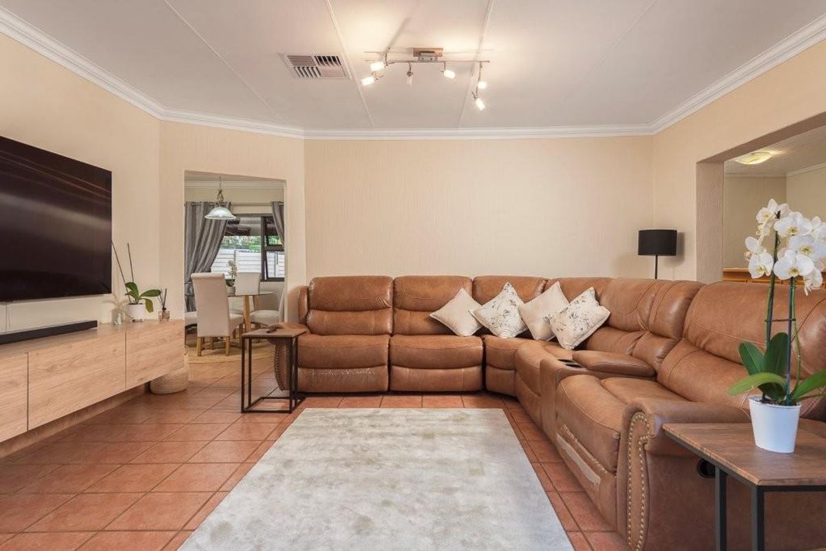 Spacious living room featuring tiled flooring, crown molding, and recessed ceiling lighting, with an open-plan layout connecting to the adjacent dining area.