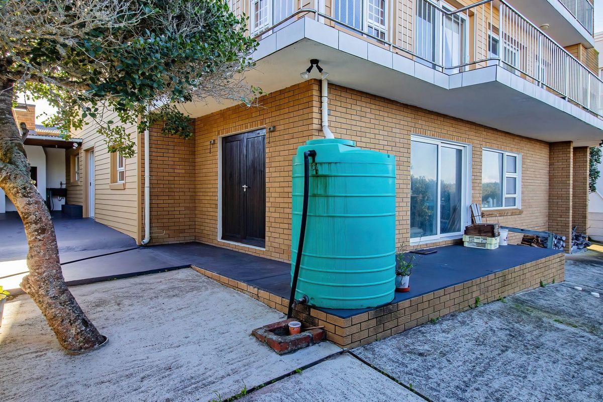 Exterior view of the property featuring a brick facade, a raised patio area, and a large water storage tank.
