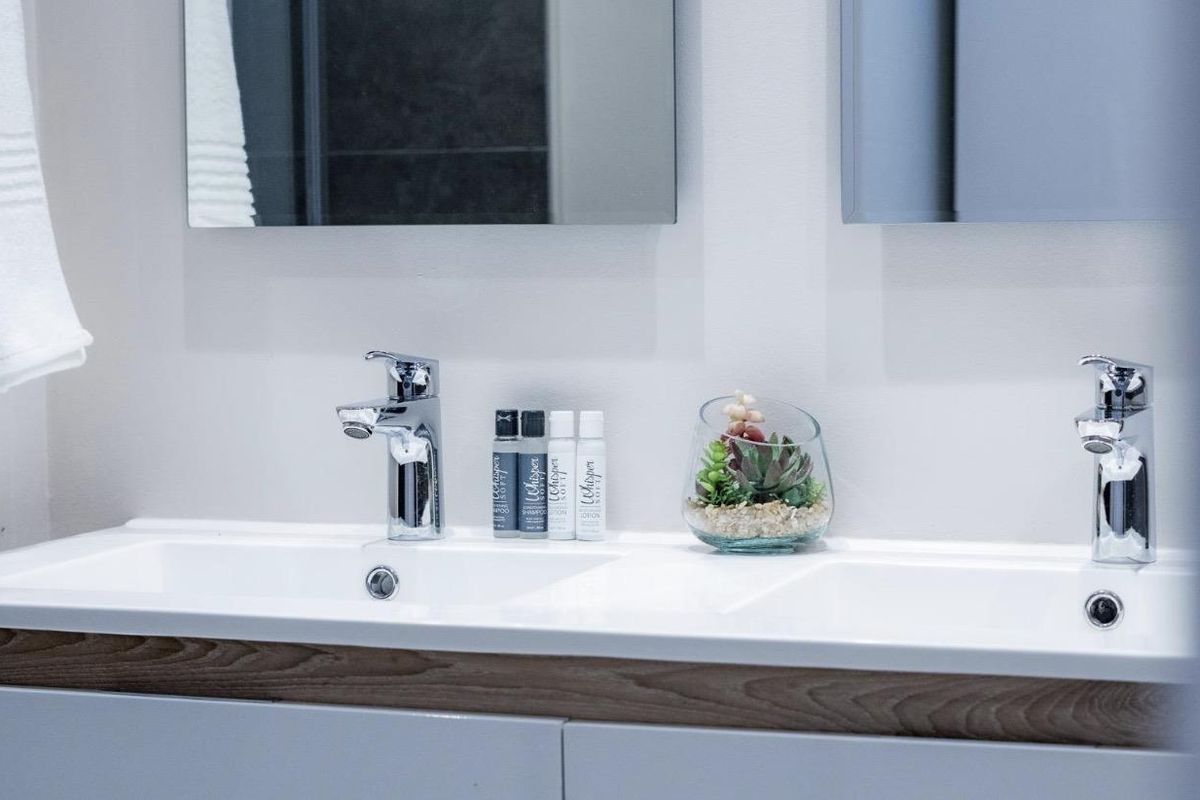 A modern bathroom vanity featuring a double sink setup with chrome faucets and wall-mounted mirrors.